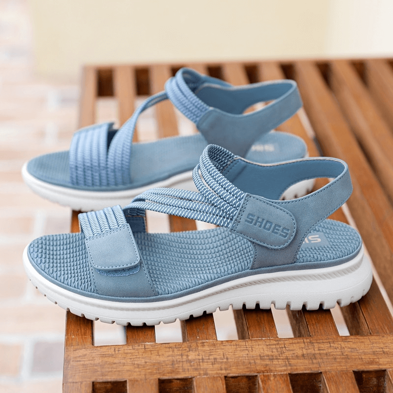 Light blue sport women's sandals with Velcro on wooden bench, featuring PU leather and TPR sole for comfort and style.